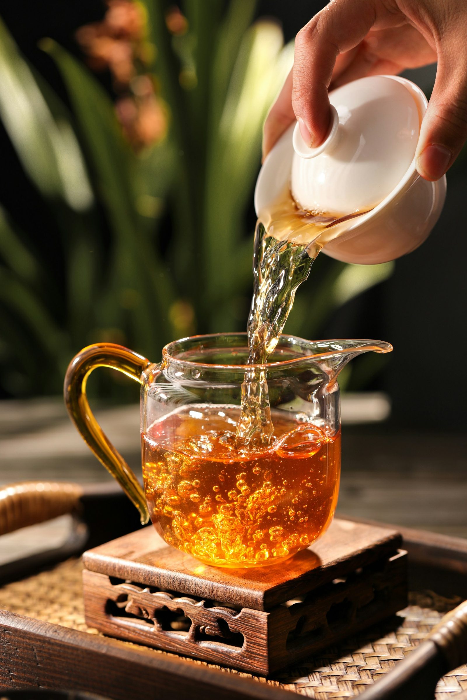 Thé versé d’un gaiwan dans un pichet en verre